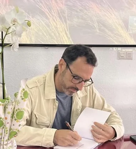 César Reyes López firmando un libro.
