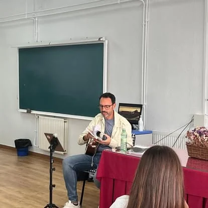 Encuentro musical con guitarra en un aula, delante de una pizarra.